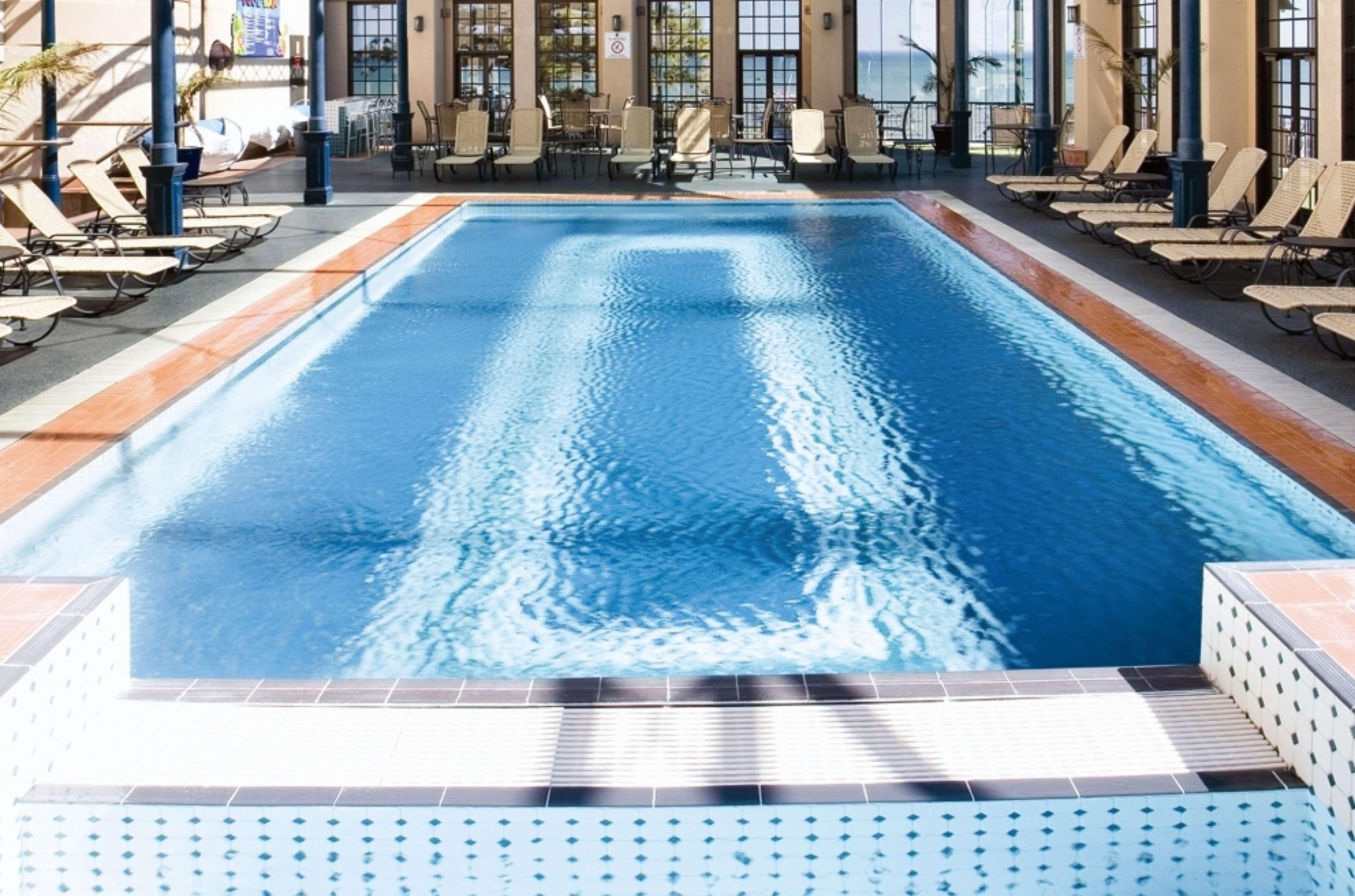 Stamford Grand Adelaide Hotel Glenelg Bagian luar foto The photo shows an indoor swimming pool with a pristine blue surface. The pool is surrounded by a tiled deck and has lounge chairs lined up along the sides. Large windows allow natural light to flood the area, creating a bright and inviting atmospher