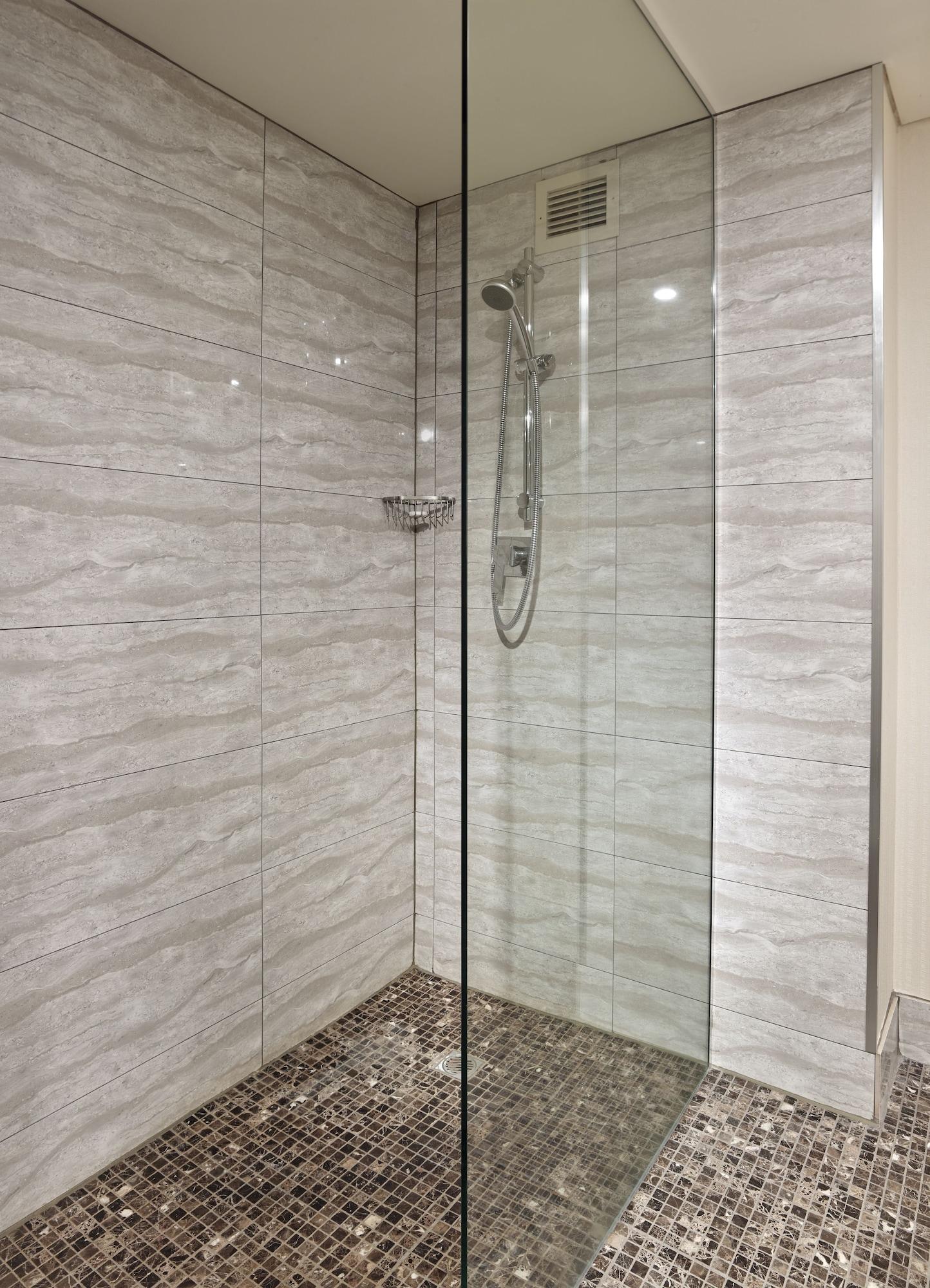 Stamford Grand Adelaide Hotel Glenelg Bagian luar foto The photo shows a modern shower enclosure with a transparent glass door. The interior features tiled walls in a light, marble-like pattern, creating a clean and sleek look. There is a showerhead mounted on the wall, and the floor appears to be tiled 