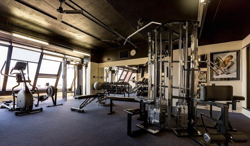 Stamford Grand Adelaide Hotel Glenelg Bagian luar foto The photo shows the interior of a gym or fitness room. It includes various exercise equipment, such as a multi-station weight machine and rowing machine. The space is well-lit with large windows allowing natural light in, and the walls are decorated 