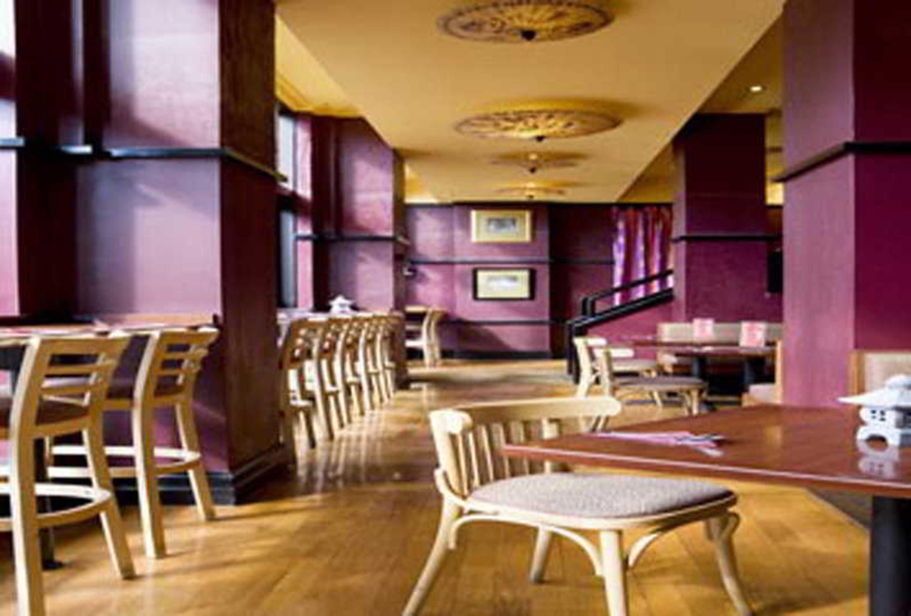 Stamford Grand Adelaide Hotel Glenelg Bagian luar foto The photo shows the interior of a restaurant. It features wooden flooring and a warm color palette, primarily using shades of burgundy and gold. There are several wooden chairs arranged around tables, with the seating area appearing spacious and invi