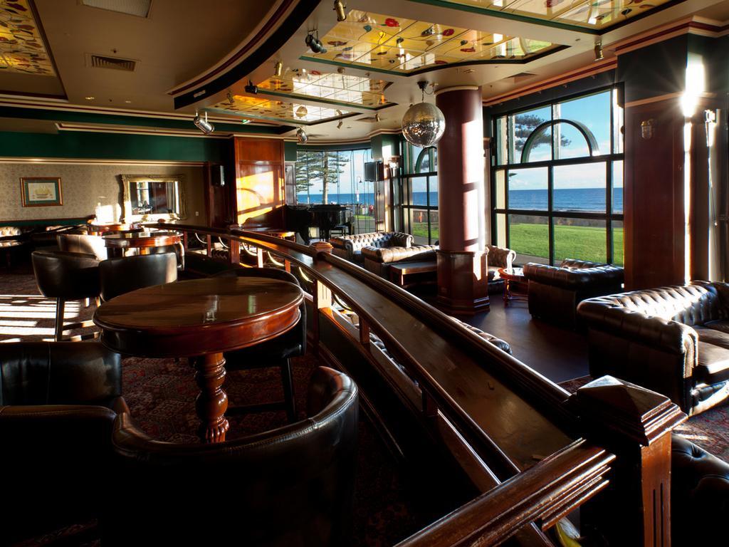 Stamford Grand Adelaide Hotel Glenelg Bagian luar foto The photo depicts a stylish and inviting interior of a lounge or bar. It features comfortable leather seating, wooden tables, and large windows that provide a view of the outdoors. The ceiling is adorned with decorative elements, and there’s a disco 